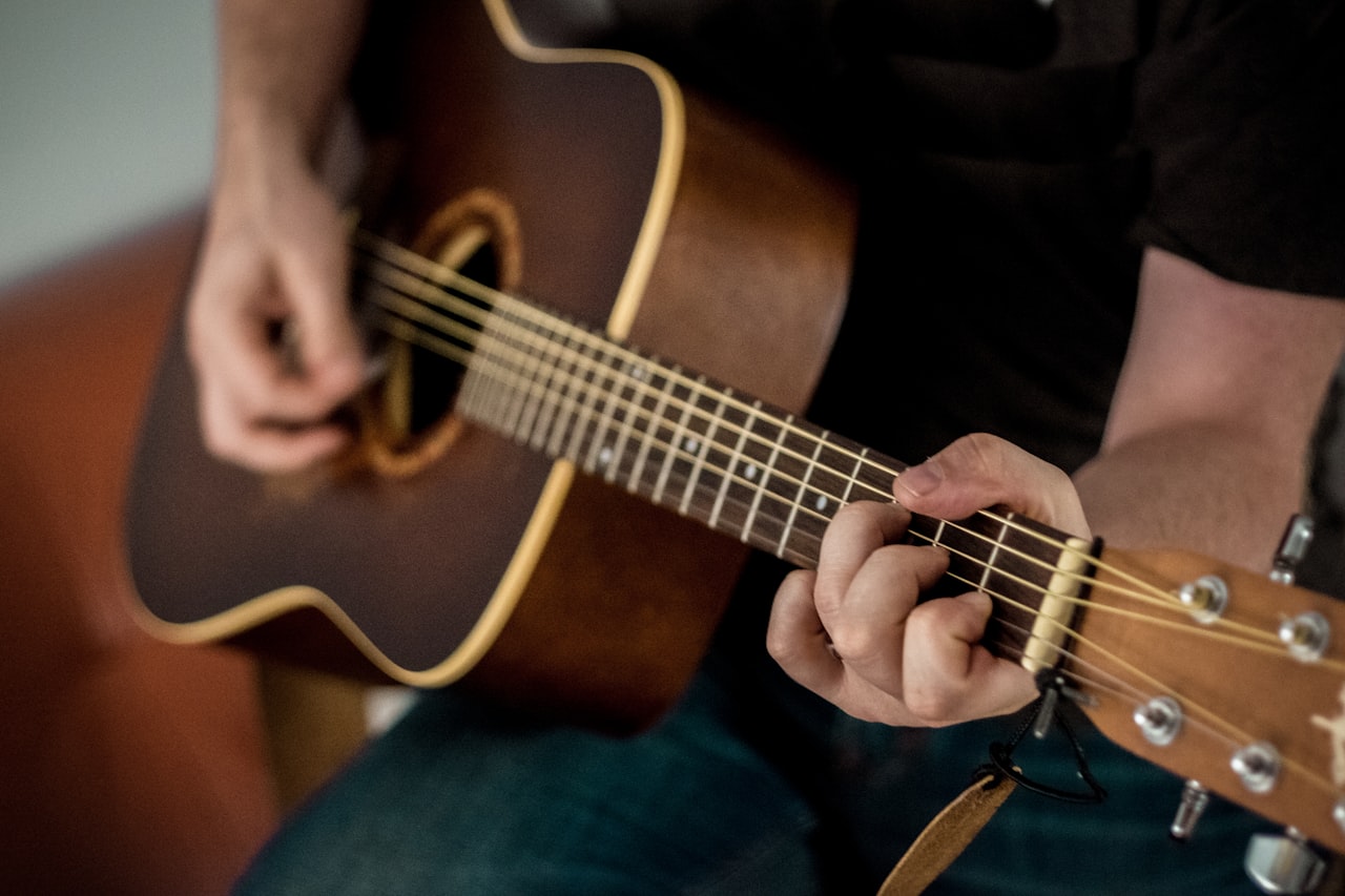 Persona aprendiendo a tocar la guitarra acústica