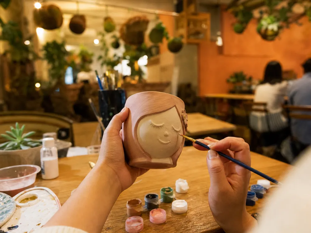 Manos pintando una maceta de cerámica